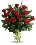 Bouquet of red roses with green leaves in a clear vase