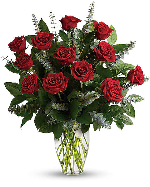 Bouquet of red roses with green leaves in a clear vase