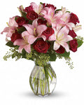 Bouquet of pink lilies and red roses in a clear vase
