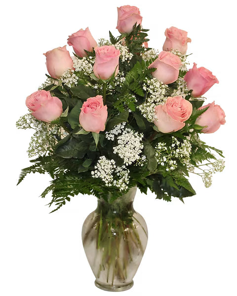 Bouquet of pink roses with green leaves and white flowers in a clear vase