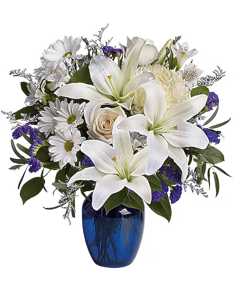 Bouquet of white lilies and roses with greenery in a blue vase
